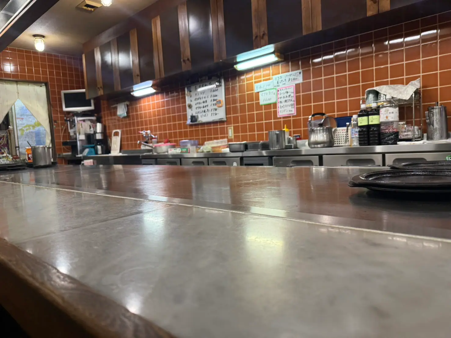 樹辺里の鉄板カウンター。テラコッタのタイル壁と木の吊り戸棚が続く店内